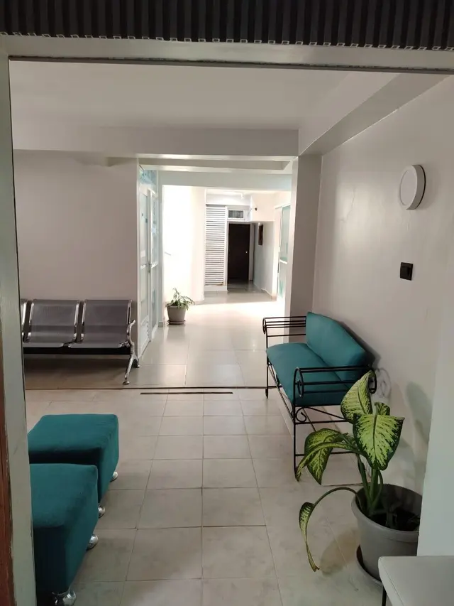 Pasillo de planta baja con sillones turquesa y plantas