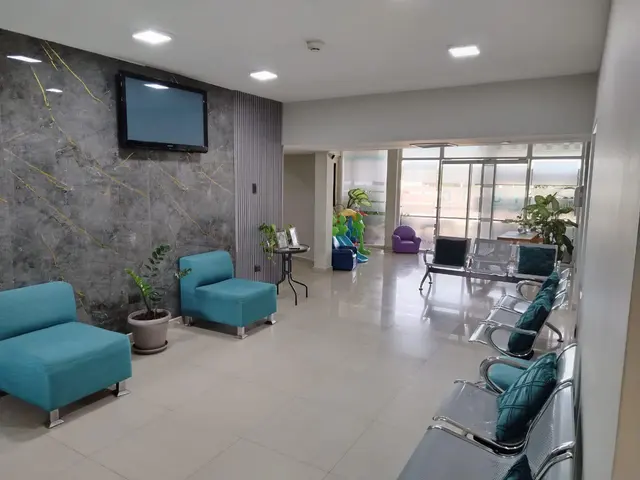 Recepción y sala de espera del Instituto Médico Mene Grande, con sillones turquesa y área infantil